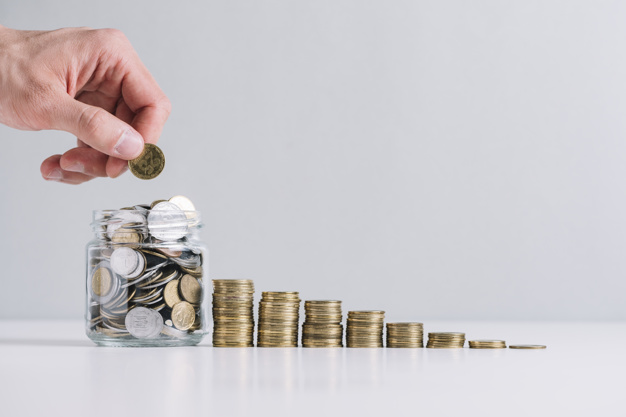 person-s-hand-putting-money-glass-jar-near-decreasing-stacked-coins_23-2147919232